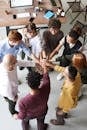 A diverse group of professionals joins hands in a team-building exercise indoors.